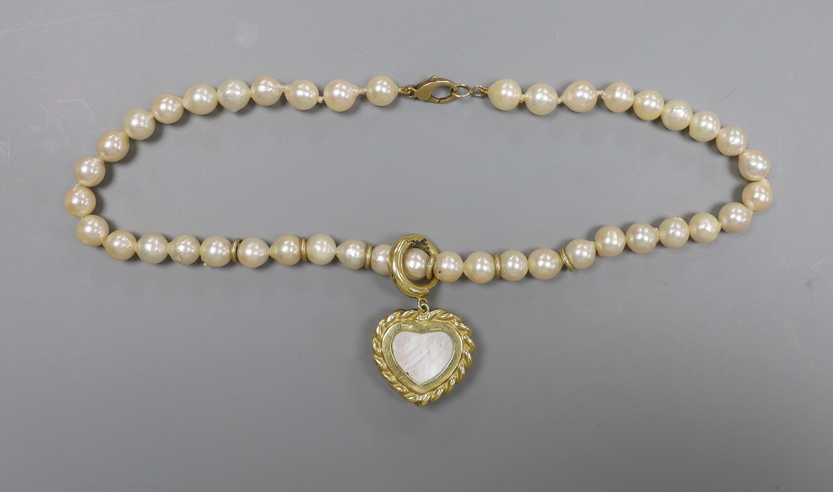 A 1960's single strand cultured pearl necklace, with an 18ct gold and mother of pearl set heart shaped pendant, necklace 39cm, pendant 25mm, gross weight 62.1 grams.